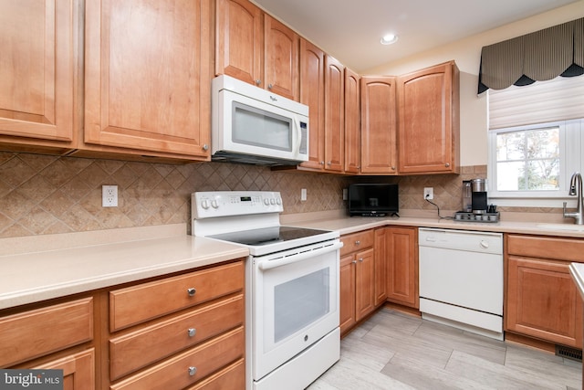 kitchen featuring backsplash, white appliances, and sink