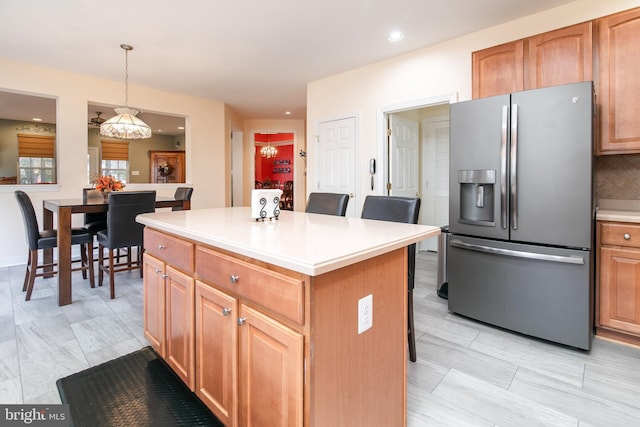 kitchen featuring a kitchen breakfast bar, decorative light fixtures, backsplash, a kitchen island, and stainless steel fridge