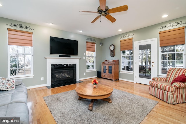 living room featuring wood-type flooring, ceiling fan, and a high end fireplace