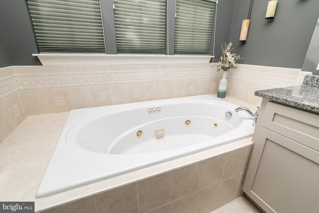 bathroom featuring a relaxing tiled tub, vanity, and tile patterned floors