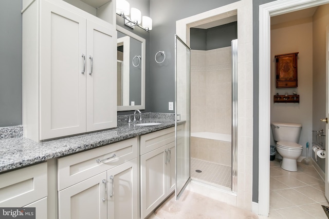 bathroom featuring toilet, vanity, tile patterned floors, and a shower with door