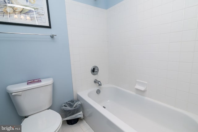 bathroom featuring toilet, tiled shower / bath combo, and tile patterned flooring