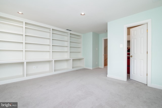 spare room featuring light colored carpet and built in features