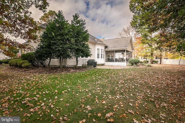 back house at dusk featuring a sunroom and a yard