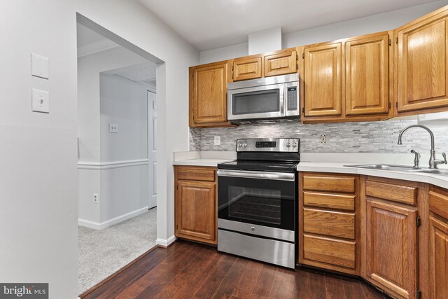 kitchen featuring sink, dark wood-type flooring, backsplash, and appliances with stainless steel finishes