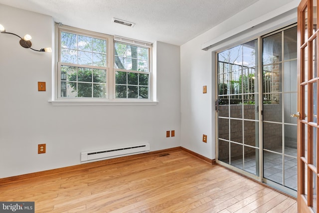 interior space featuring a textured ceiling, baseboard heating, and light wood-type flooring