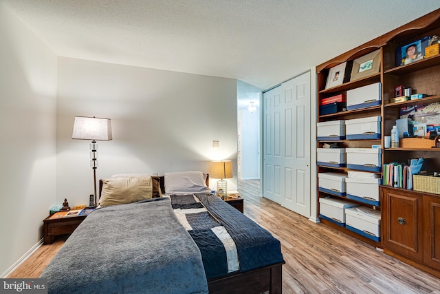 bedroom featuring light hardwood / wood-style flooring, a textured ceiling, and a closet