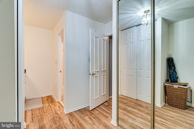 hall with a textured ceiling and light hardwood / wood-style flooring