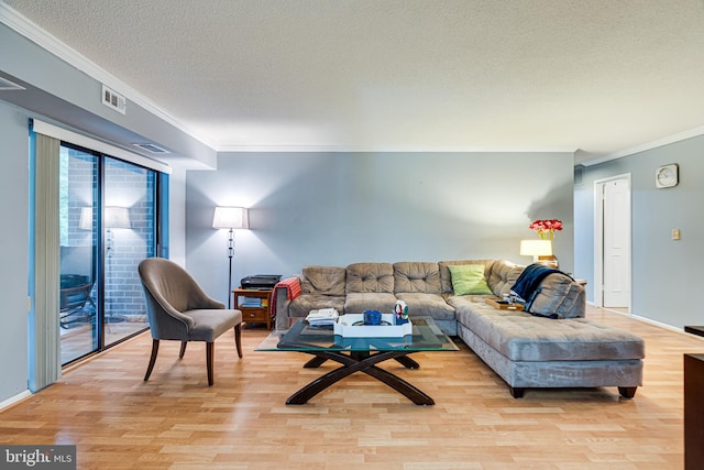 living room with crown molding, a textured ceiling, and light wood-type flooring