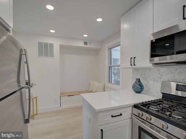 kitchen featuring decorative backsplash, kitchen peninsula, light hardwood / wood-style flooring, white cabinetry, and appliances with stainless steel finishes