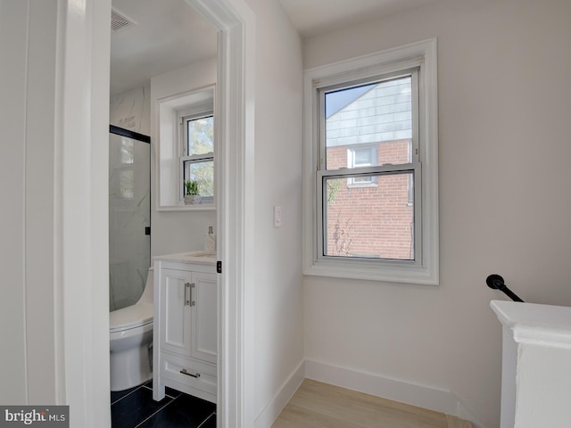 bathroom featuring walk in shower, hardwood / wood-style floors, plenty of natural light, and toilet