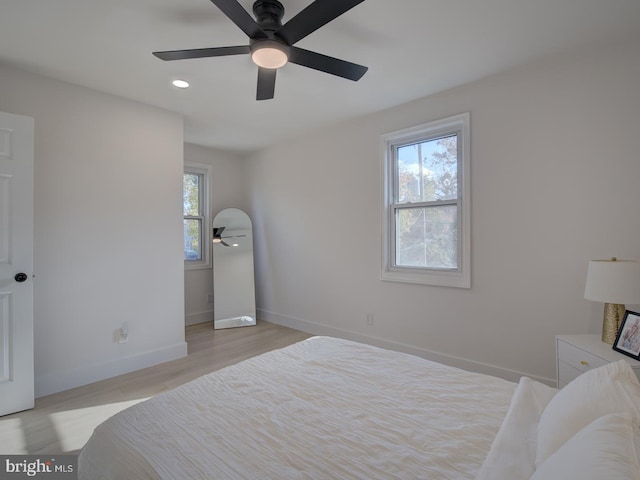 bedroom featuring multiple windows, ceiling fan, and light hardwood / wood-style flooring