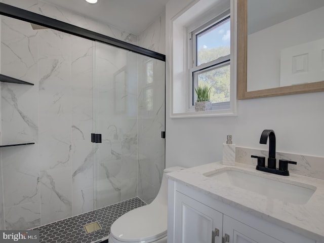 bathroom featuring toilet, vanity, and a shower with door