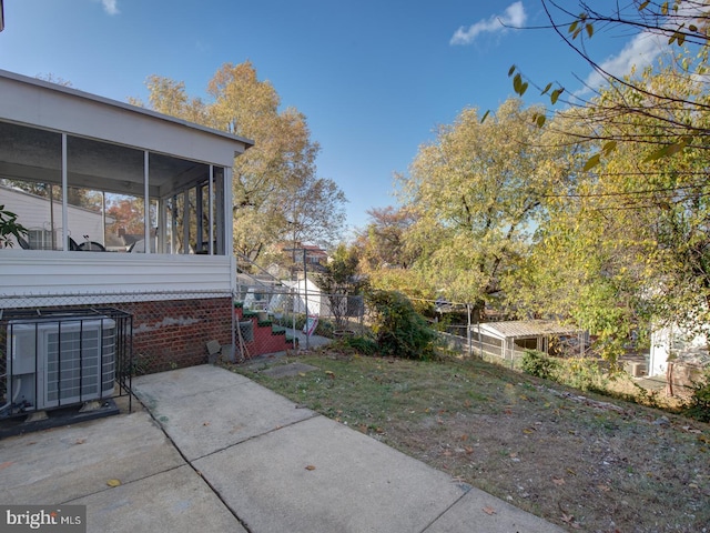 view of yard featuring a patio, central AC, and a sunroom