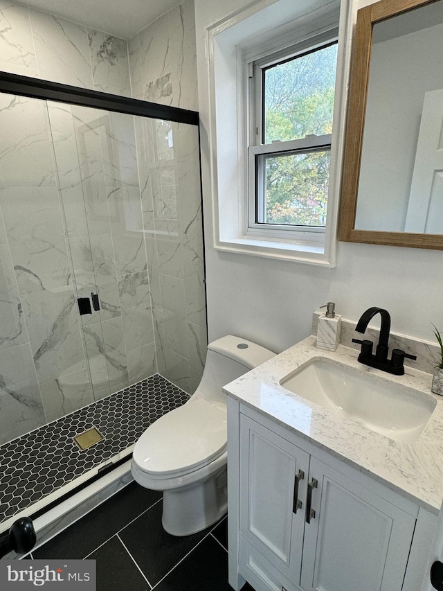 bathroom with a shower with shower door, vanity, toilet, and tile patterned floors