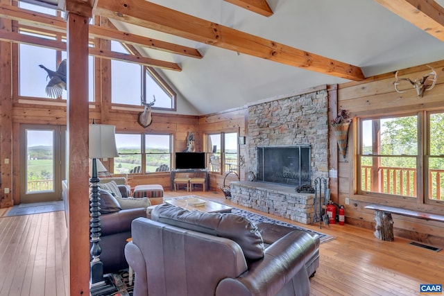 living room featuring beamed ceiling, light wood-type flooring, high vaulted ceiling, and a healthy amount of sunlight