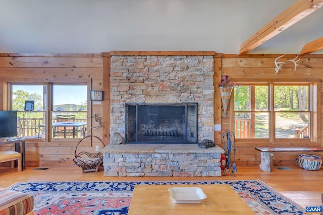 living room with wood walls, wood-type flooring, beamed ceiling, and a fireplace