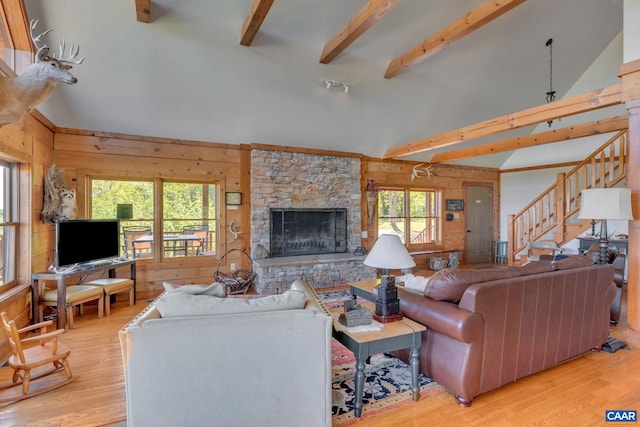 living room featuring a stone fireplace, light hardwood / wood-style flooring, and a wealth of natural light