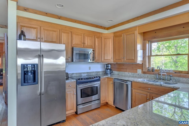 kitchen featuring light brown cabinets, light stone countertops, light wood-type flooring, sink, and stainless steel appliances