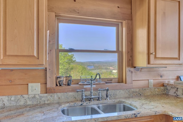 kitchen with light stone countertops, sink, light brown cabinetry, and wooden walls