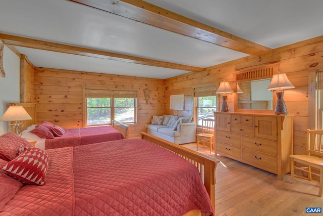 bedroom featuring light hardwood / wood-style flooring, multiple windows, wood walls, and beam ceiling