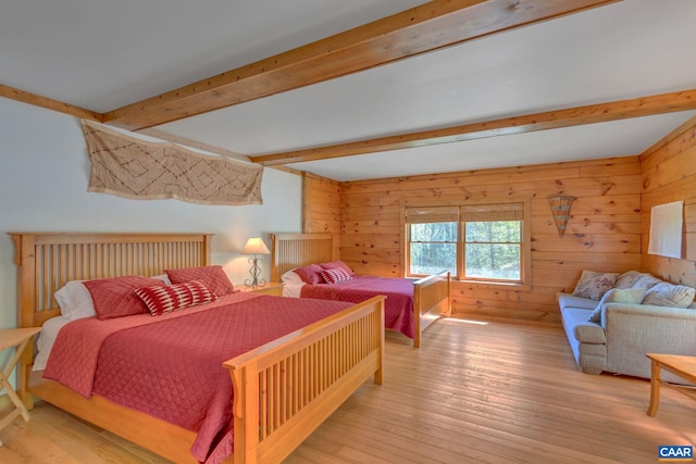 bedroom featuring wood walls, beamed ceiling, and light wood-type flooring