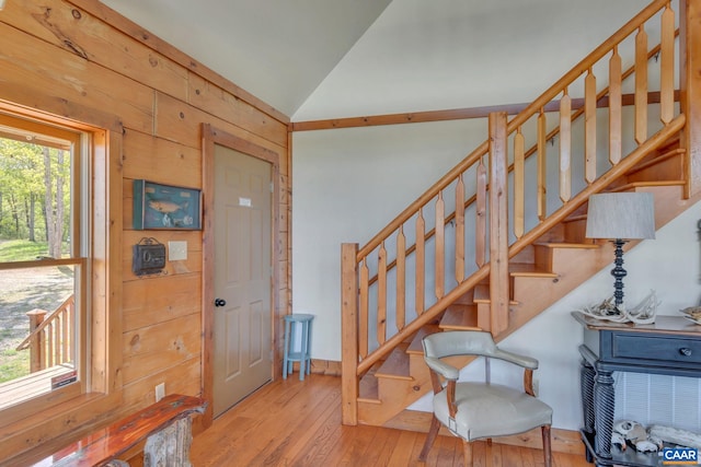 foyer entrance featuring lofted ceiling, light wood-type flooring, and wood walls