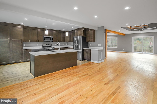 kitchen featuring stainless steel appliances, sink, pendant lighting, and light hardwood / wood-style flooring