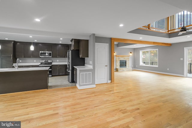 kitchen featuring stainless steel appliances, sink, pendant lighting, and light hardwood / wood-style floors