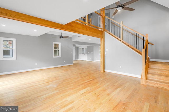 unfurnished living room featuring ceiling fan, light hardwood / wood-style floors, and vaulted ceiling with beams