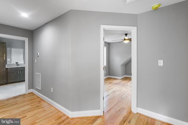 hallway with sink and light wood-type flooring