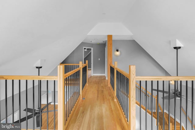 hall with lofted ceiling, an upstairs landing, and wood finished floors