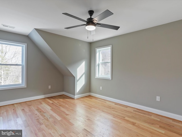 additional living space featuring light wood-type flooring, ceiling fan, baseboards, and visible vents