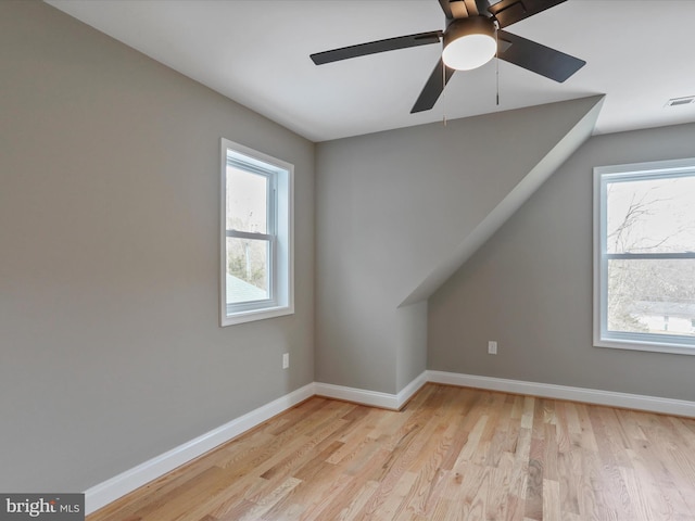 additional living space with baseboards, light wood-style flooring, visible vents, and a ceiling fan
