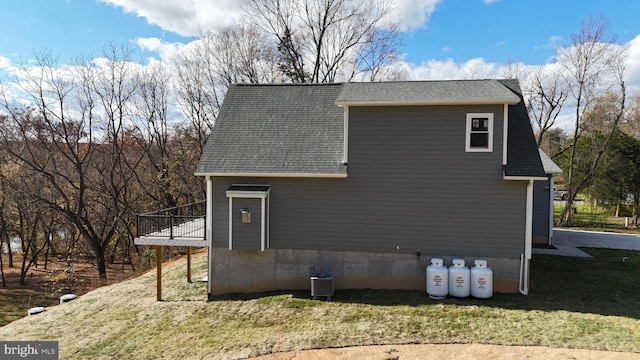 view of side of home featuring central AC, a deck, and a lawn