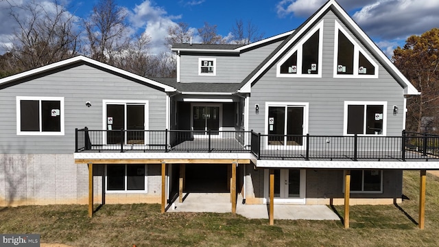 back of property with a wooden deck, a patio area, and a lawn