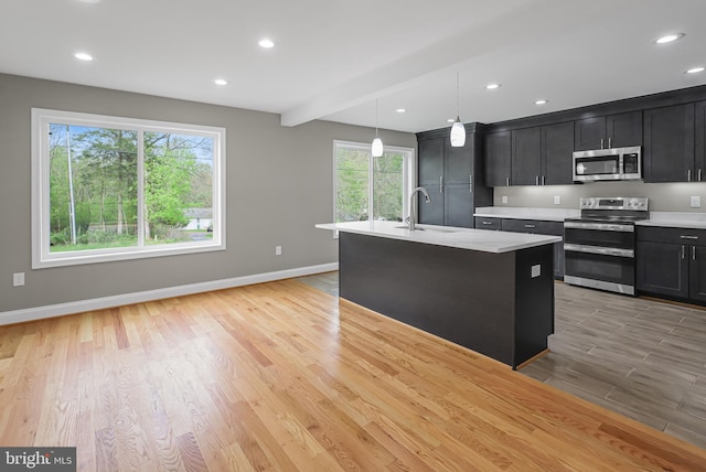 kitchen with a sink, stainless steel appliances, light countertops, and a healthy amount of sunlight