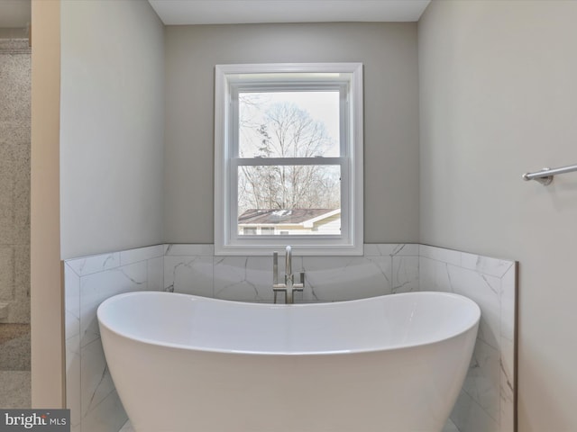 bathroom featuring tile walls and a tub to relax in