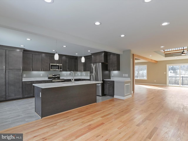 kitchen featuring stainless steel appliances, decorative light fixtures, sink, and light wood-type flooring
