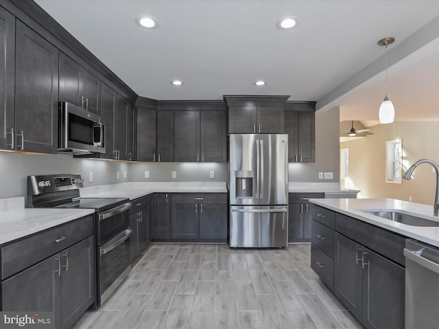 kitchen with appliances with stainless steel finishes, sink, pendant lighting, and ceiling fan