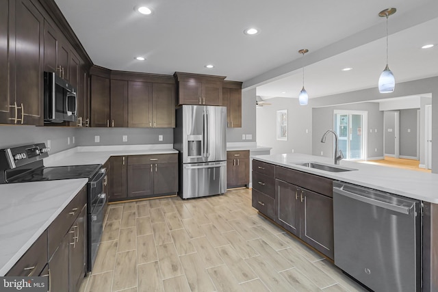 kitchen with dark brown cabinetry, sink, light stone counters, decorative light fixtures, and stainless steel appliances