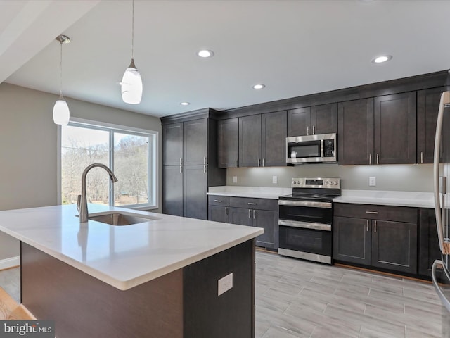 kitchen featuring a sink, recessed lighting, an island with sink, light countertops, and appliances with stainless steel finishes