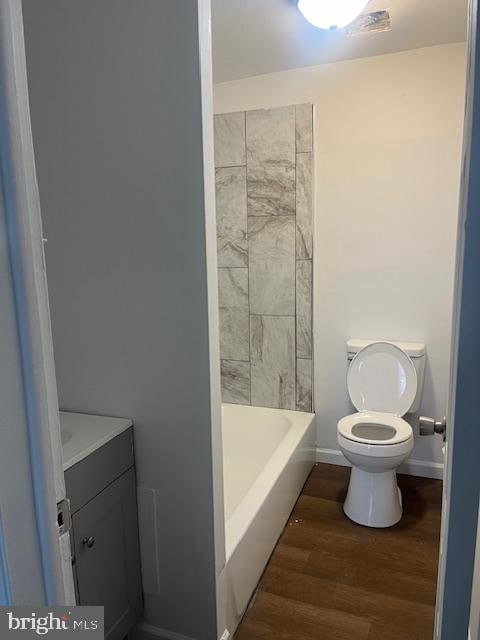 bathroom featuring a tub to relax in, vanity, hardwood / wood-style flooring, and toilet