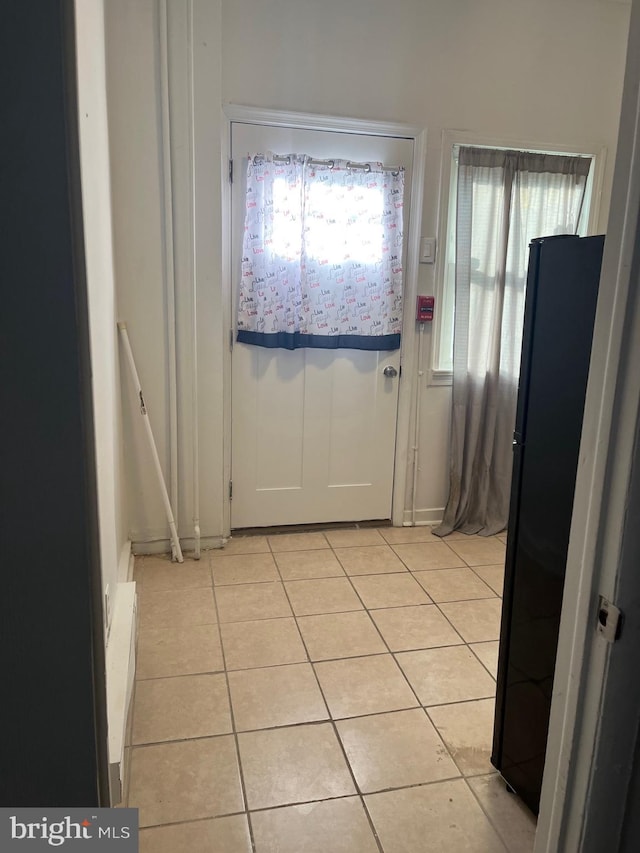 doorway to outside featuring a baseboard heating unit and light tile patterned floors