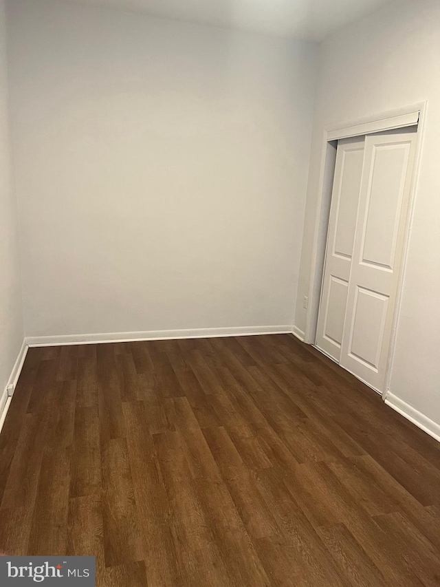 unfurnished bedroom with a closet and dark wood-type flooring