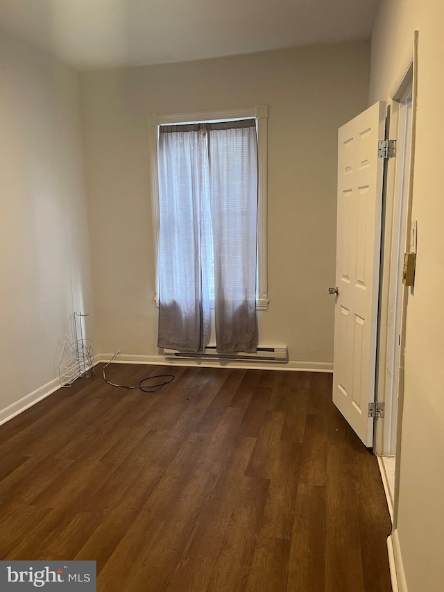 empty room with baseboard heating and dark wood-type flooring