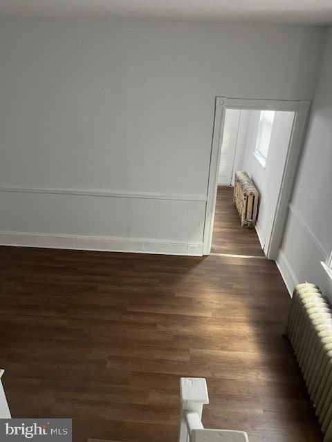 spare room with dark hardwood / wood-style flooring and radiator heating unit