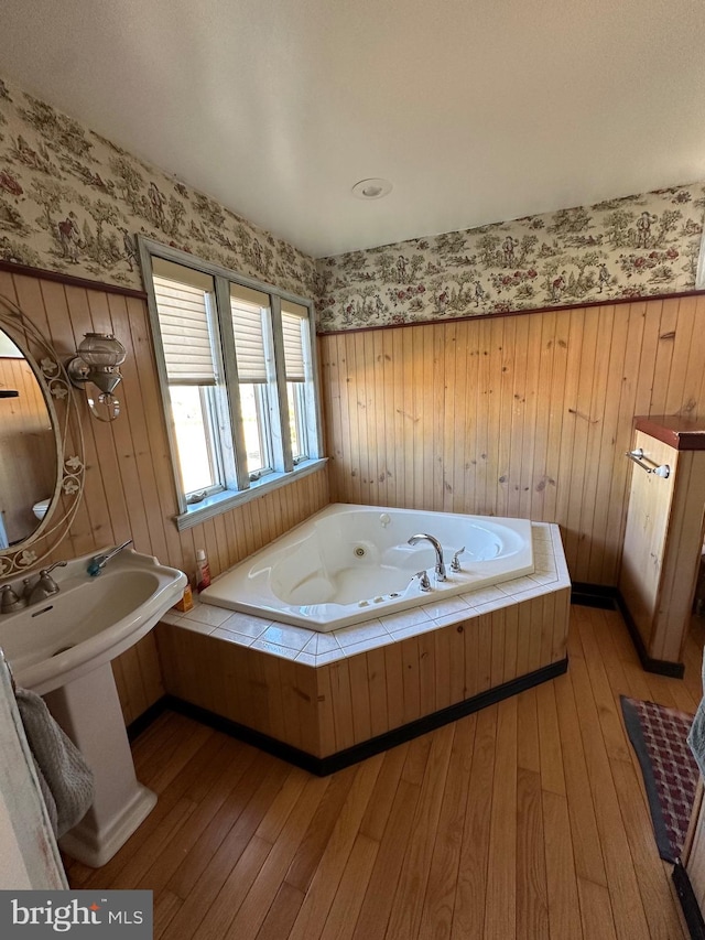 bathroom featuring a tub, wood-type flooring, and wooden walls