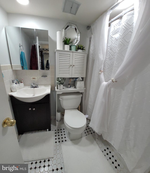 bathroom featuring tasteful backsplash, tile patterned floors, vanity, and toilet