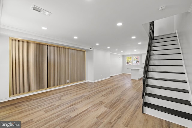 basement with crown molding and light wood-type flooring